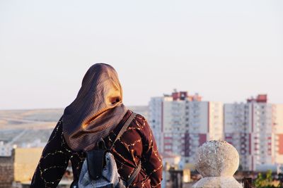 Woman looking at cityscape against clear sky