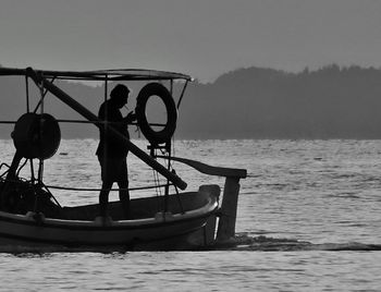 Silhouette of man standing on boat in sea