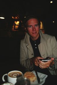 Portrait of smiling man using phone while having food in restaurant