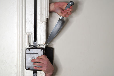 Cropped hands of thief cutting door chain with knife