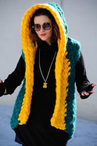 Portrait of a brunette girl in sunglasses, dressed in a warm, bright, long vest of large knitting