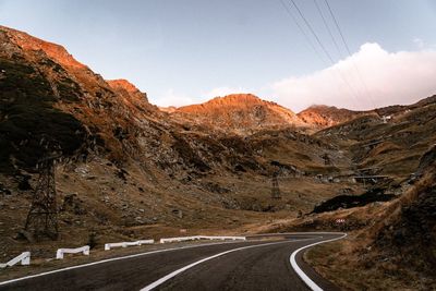 Road leading towards mountains against sky