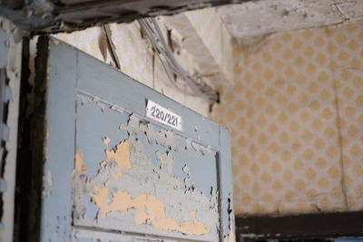 Low angle view of numbers on old wooden door in abandoned house