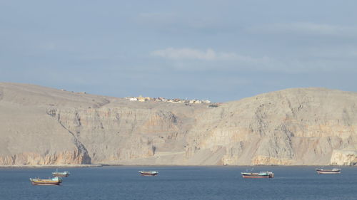 Boats moving in sea against cloudy sky