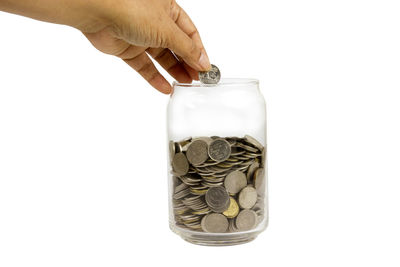 Close-up of hand holding coin against white background