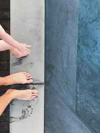 Low section of women by child on concrete wall