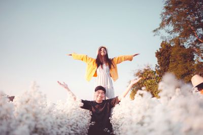 Portrait of smiling couple standing with arms outstretched amidst smoke