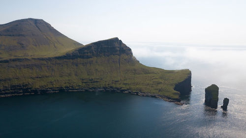 Scenic view of sea by mountains against sky