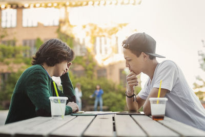 Side view of teenage boys studying at table outdoors