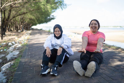 Portrait of smiling friends sitting on rock