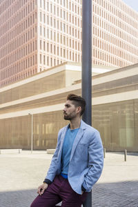 Portrait of young man standing against building