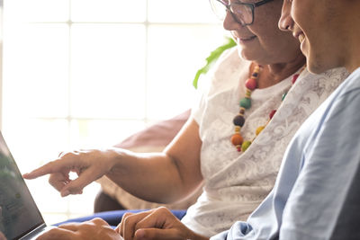 Midsection of smiling grandmother and grandson using laptop at home