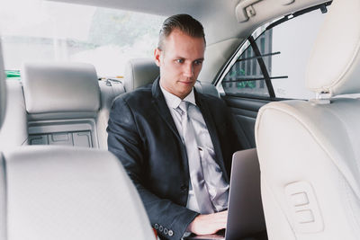 Young businessman using laptop while sitting in car