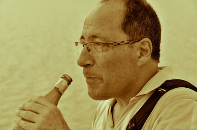 Close-up of man wearing eyeglasses while having drink from bottle