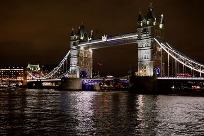 Illuminated tower bridge over river at night