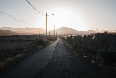 Road leading towards mountains against clear sky