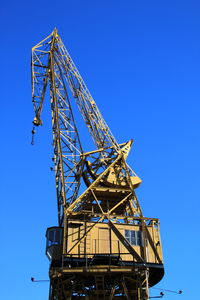 Low angle view of crane against clear blue sky