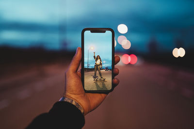 Midsection of woman photographing illuminated smart phone