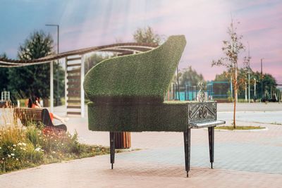 Empty chairs and tables in park against sky