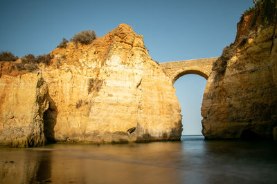 Arch on rock formation against sky