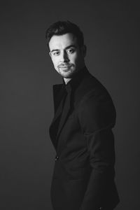 Portrait of young man standing against black background