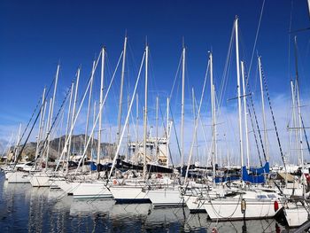 Sailboats moored at harbor against clear blue sky