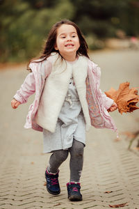 Full length of woman running on road while holding autumn leaves