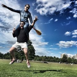 Cheerful man carrying girlfriend on shoulders while jumping at richmond park