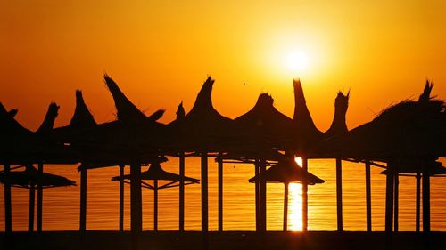 Silhouette parasols against orange sky during sunset