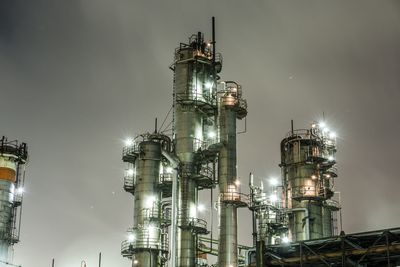 Low angle view of illuminated factory against sky at night