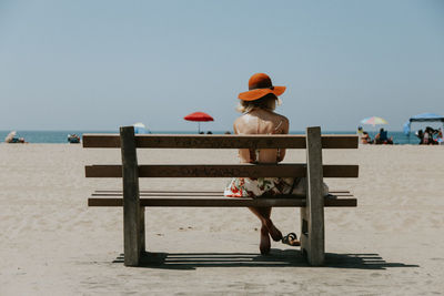 Rear view of person on beach against clear sky