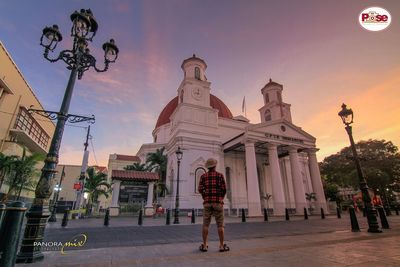 People on street against buildings in city at sunset