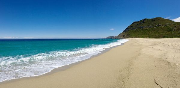 Scenic view of beach against clear blue sky