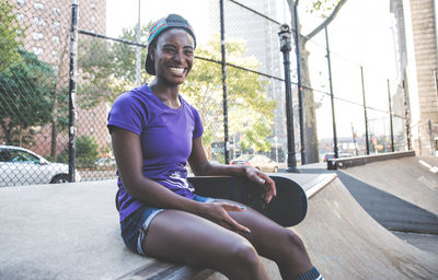 Smiling young woman sitting on wall