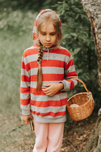 Upset or focused eight year old kid girl mushroom picker is seek for and picking mushrooms