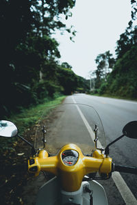 Motor scooter parked on roadside against trees