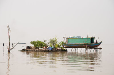 Man on boat moored in water against clear sky