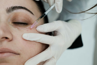 Cosmetologist applying eye mesotherapy to female patient