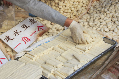 Cropped image of vendor hand arranging tofu at market stall