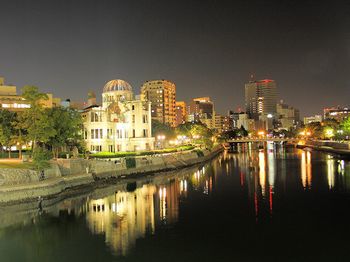 Illuminated buildings by pond at peace memorial park