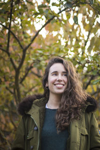 Portrait of a smiling young woman against trees