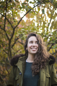 Smiling woman standing against trees