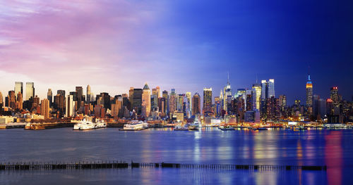City at waterfront against cloudy sky