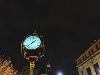 Low angle view of illuminated clock tower at night