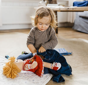 Cute girl playing with doll at home