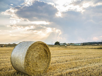 Hay bales on field against sky