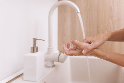 Cropped hand washing hands in sink