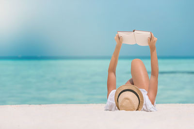 Man relaxing on beach against sky