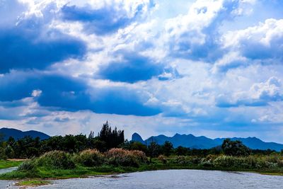 Scenic view of river by mountains against sky