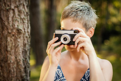 Close-up of woman photographing through camera outdoors